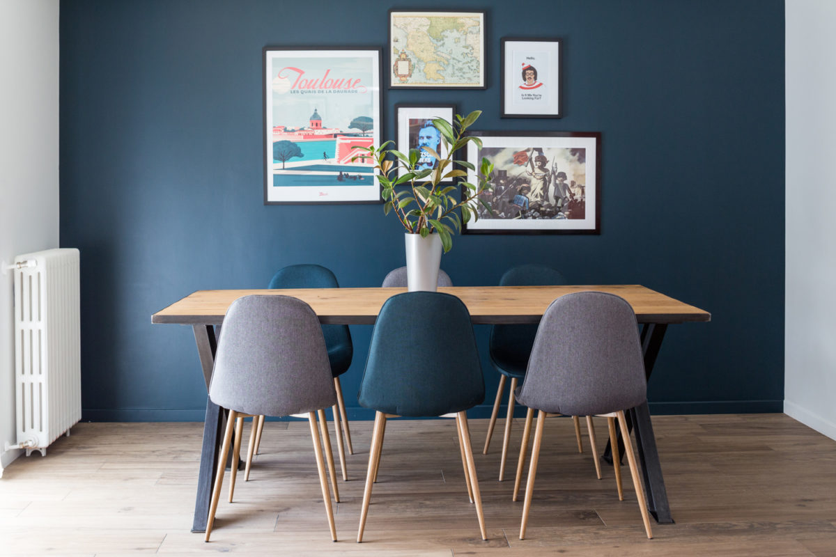 table avec chaises devant un mur bleu et ses cadres décoratifs