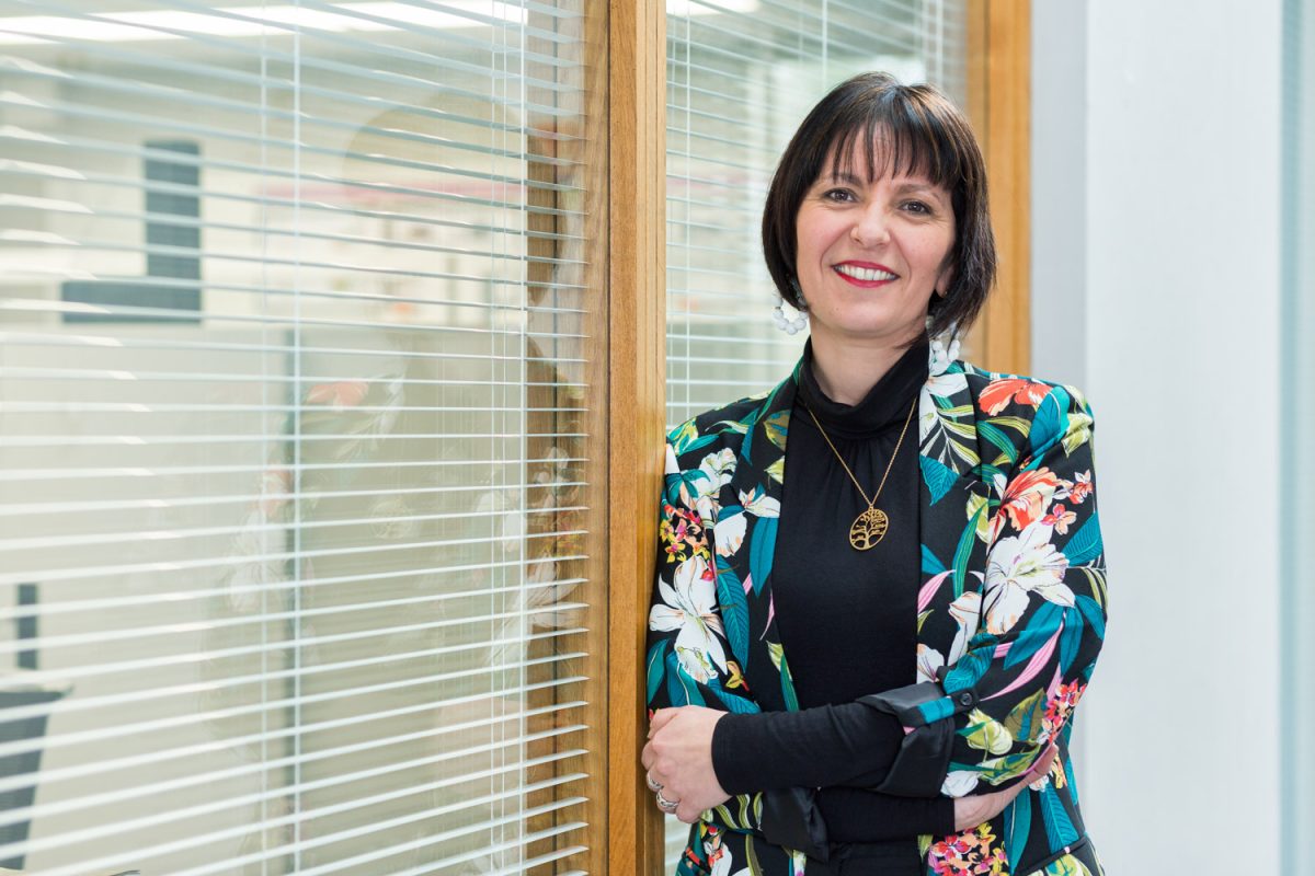 Une collaboratrice d'un grand groupe est debout dans un couloir pour la réalisation d'une photographie de portrait.