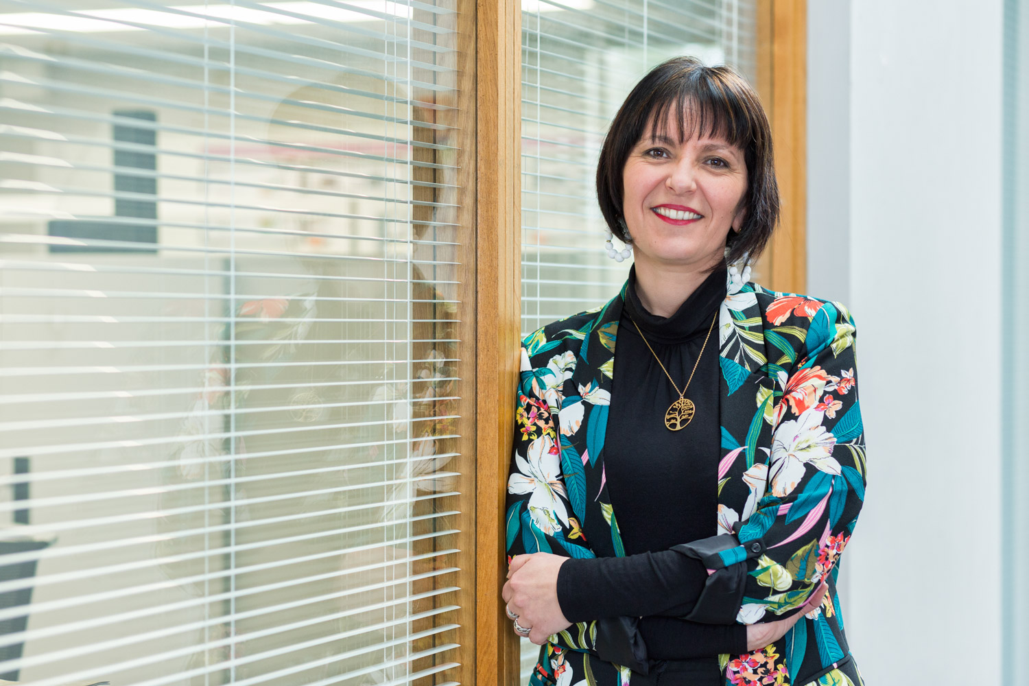 Une collaboratrice d'un grand groupe est debout dans un couloir pour la réalisation d'une photographie de portrait.