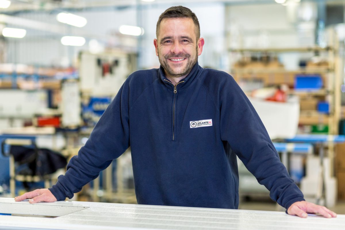 Image d'un collaborateur posant devant son outil de travail dans l'industrie.